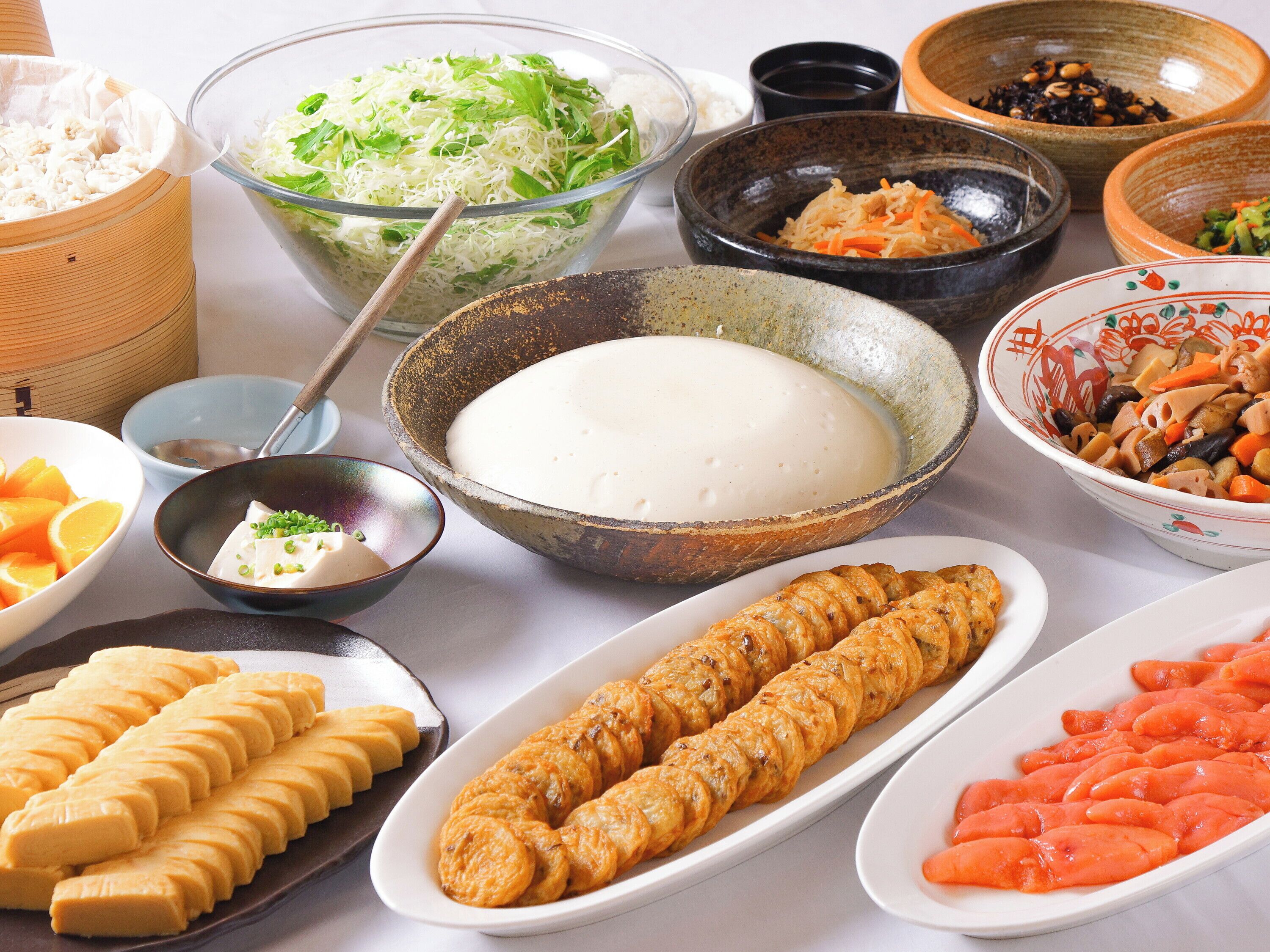 A variety of dishes including a bowl of rice, a plate of sliced meat, and several bowls of different foods.
