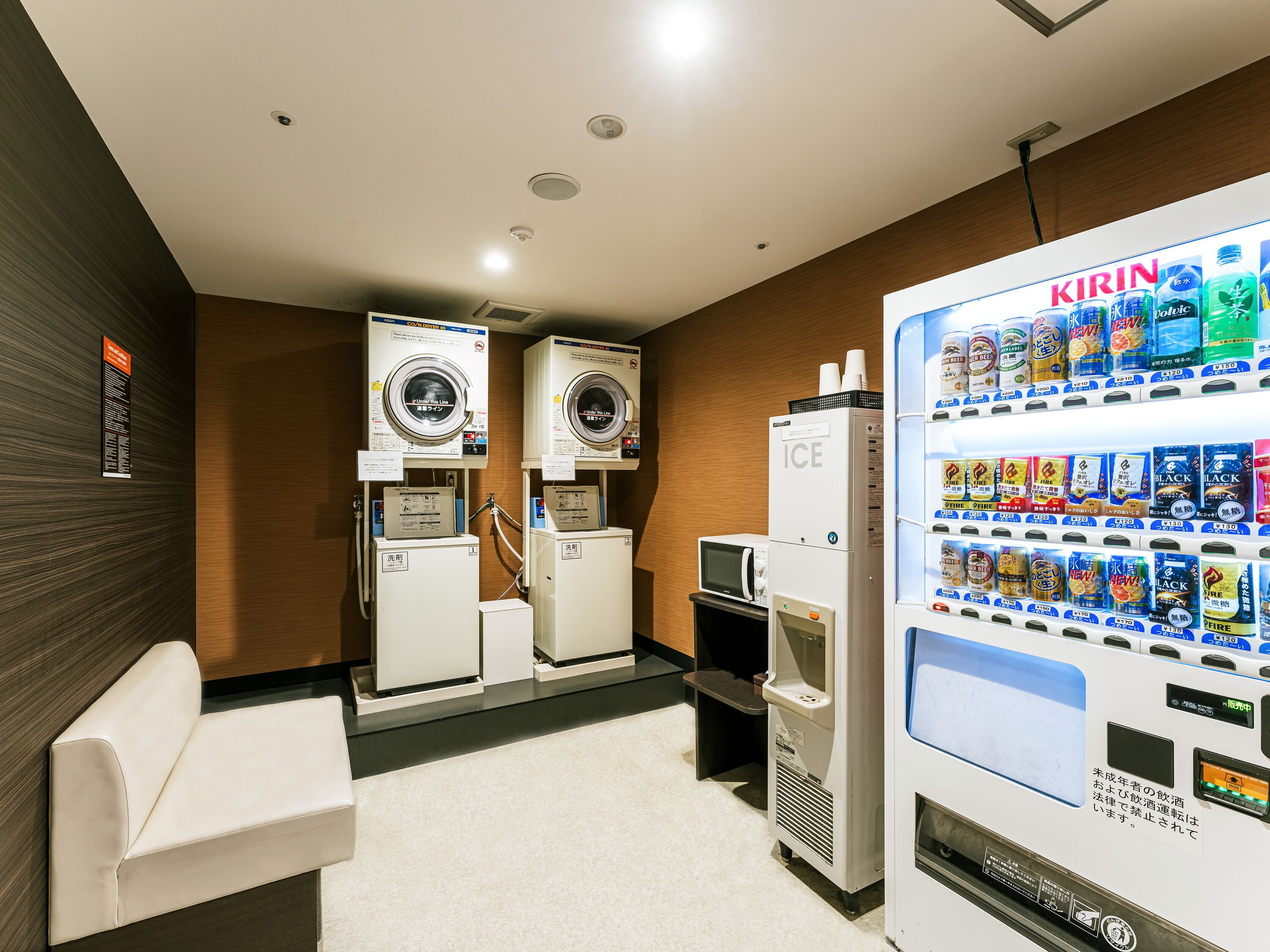 A public washroom with two washing machines, a vending machine, and a microwave.