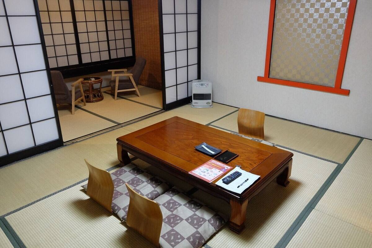 A traditional Japanese room with tatami flooring, a low wooden table, and a tatami mat bench.