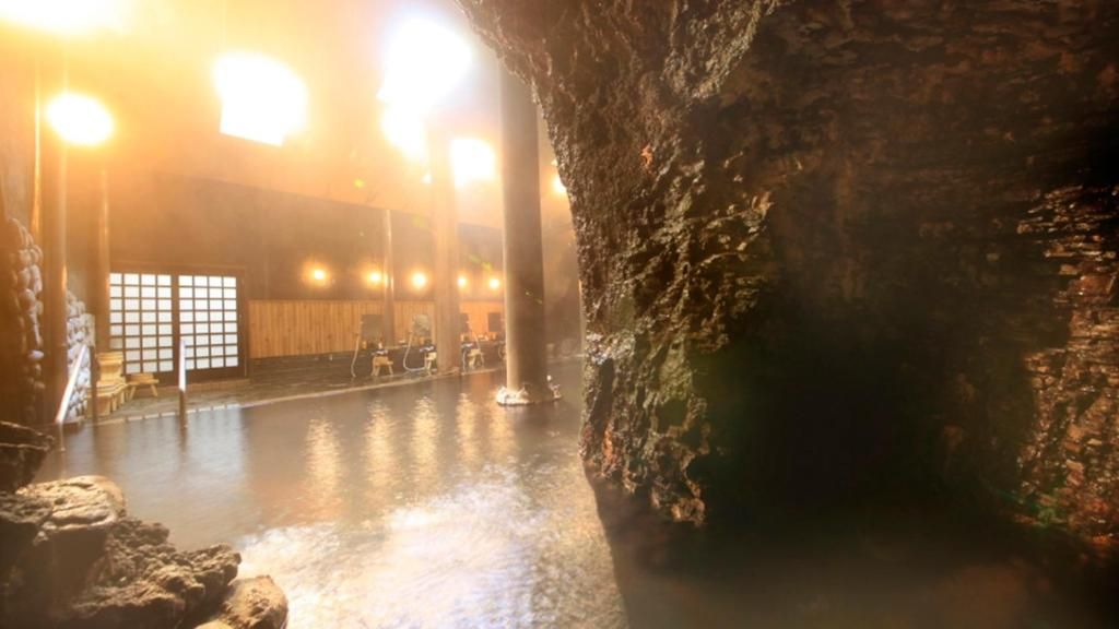 A spacious indoor area with a large rock formation, a wooden floor, and a seating area with tables and chairs.