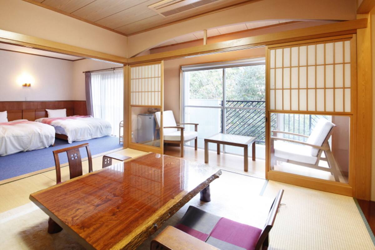 A traditional Japanese-style room with tatami flooring, a wooden table, and a balcony with sliding doors.