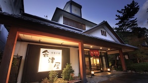A traditional Japanese building with a large illuminated sign, wooden beams, and a well-maintained garden. - The Aizuya (Nasushiobara)