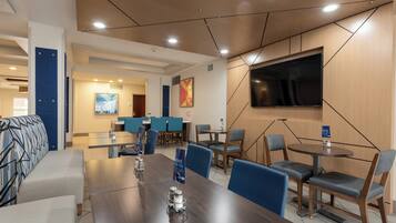 A modern conference room with a large table, chairs, a flat-screen TV, and a blue accent wall.