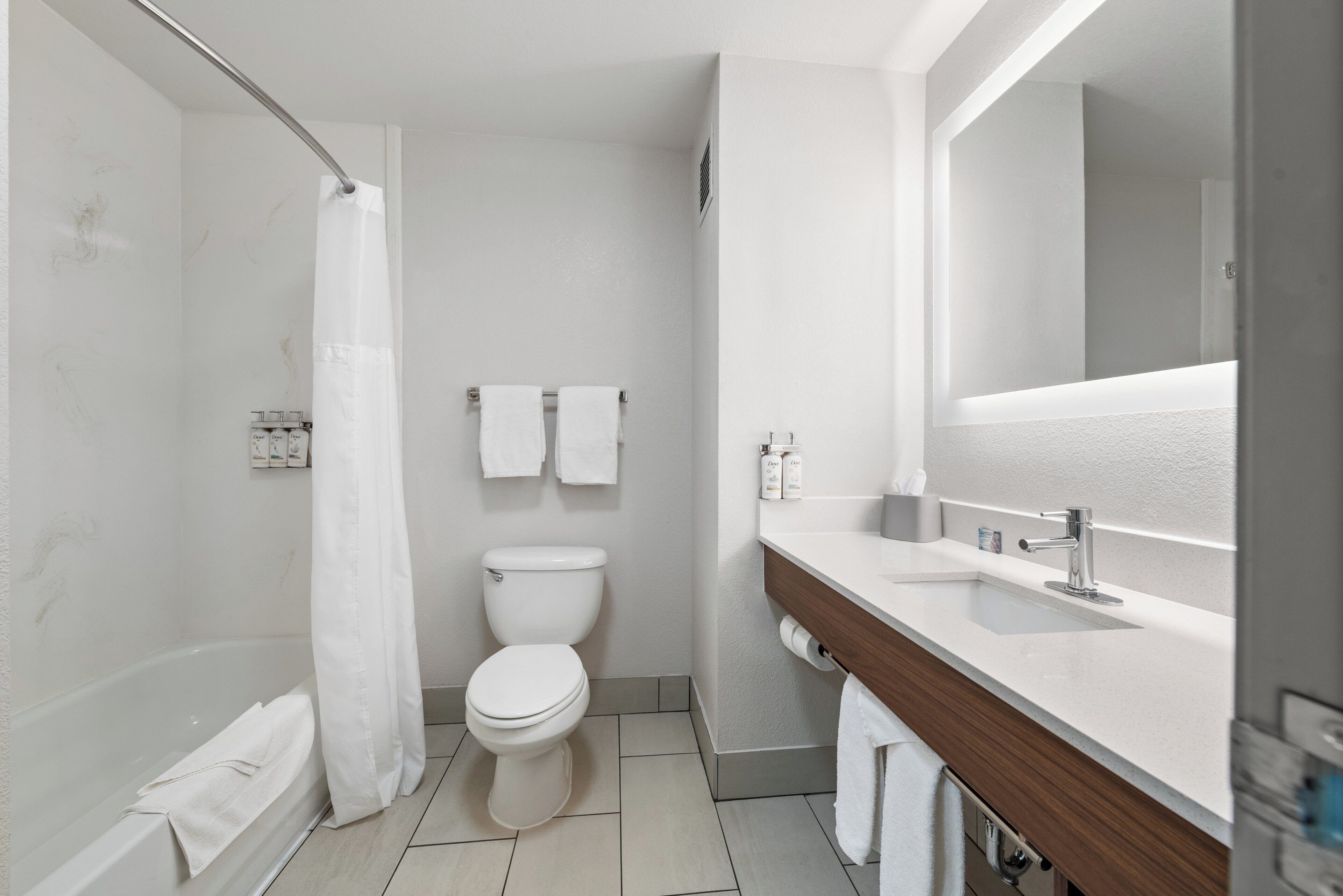 A modern bathroom with a bathtub, toilet, and a vanity with a mirror.