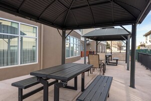 Un patio al aire libre con mesas de picnic y una zona de estar techada.