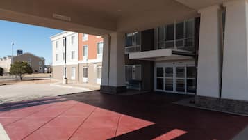 A building entrance with a red-tiled floor, a clear sky, and a sign indicating a clearance of 15'-00'.