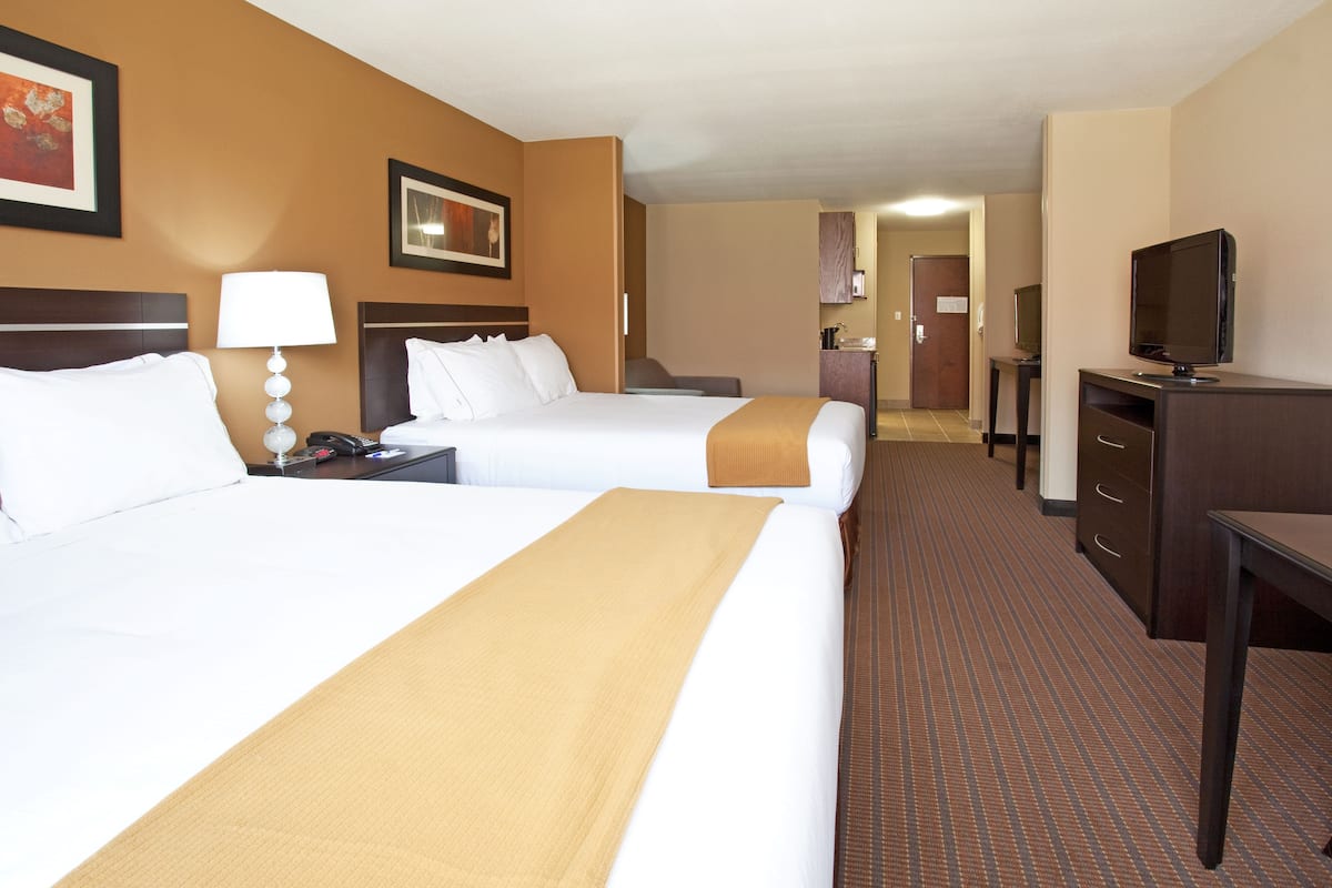 Une chambre d’hôtel avec deux lits, un bureau, une télévision et une salle de bain à l’arrière-plan.