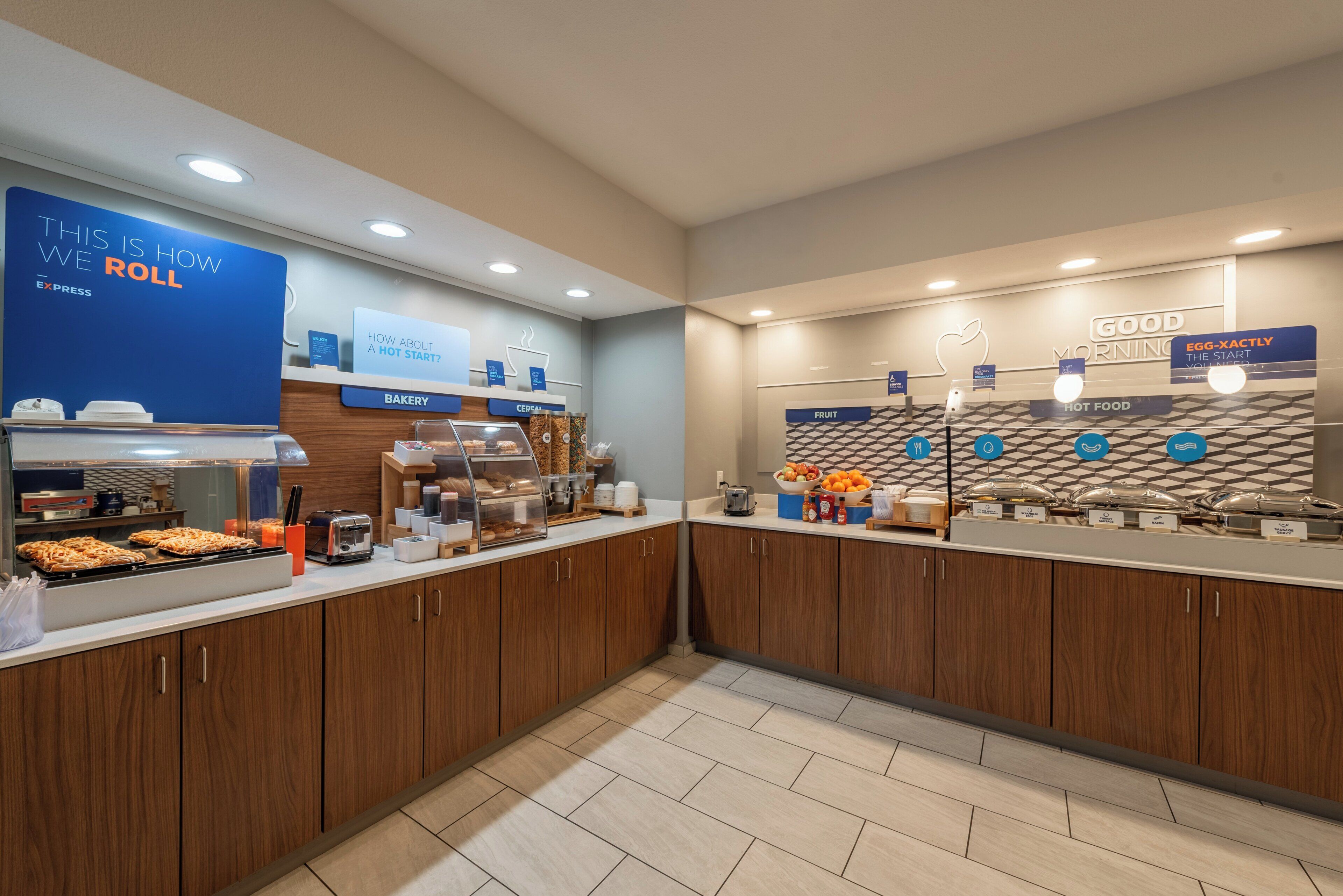 A breakfast buffet area with labeled sections for bakery, cereal, fruit, hot food, and egg-xactly.