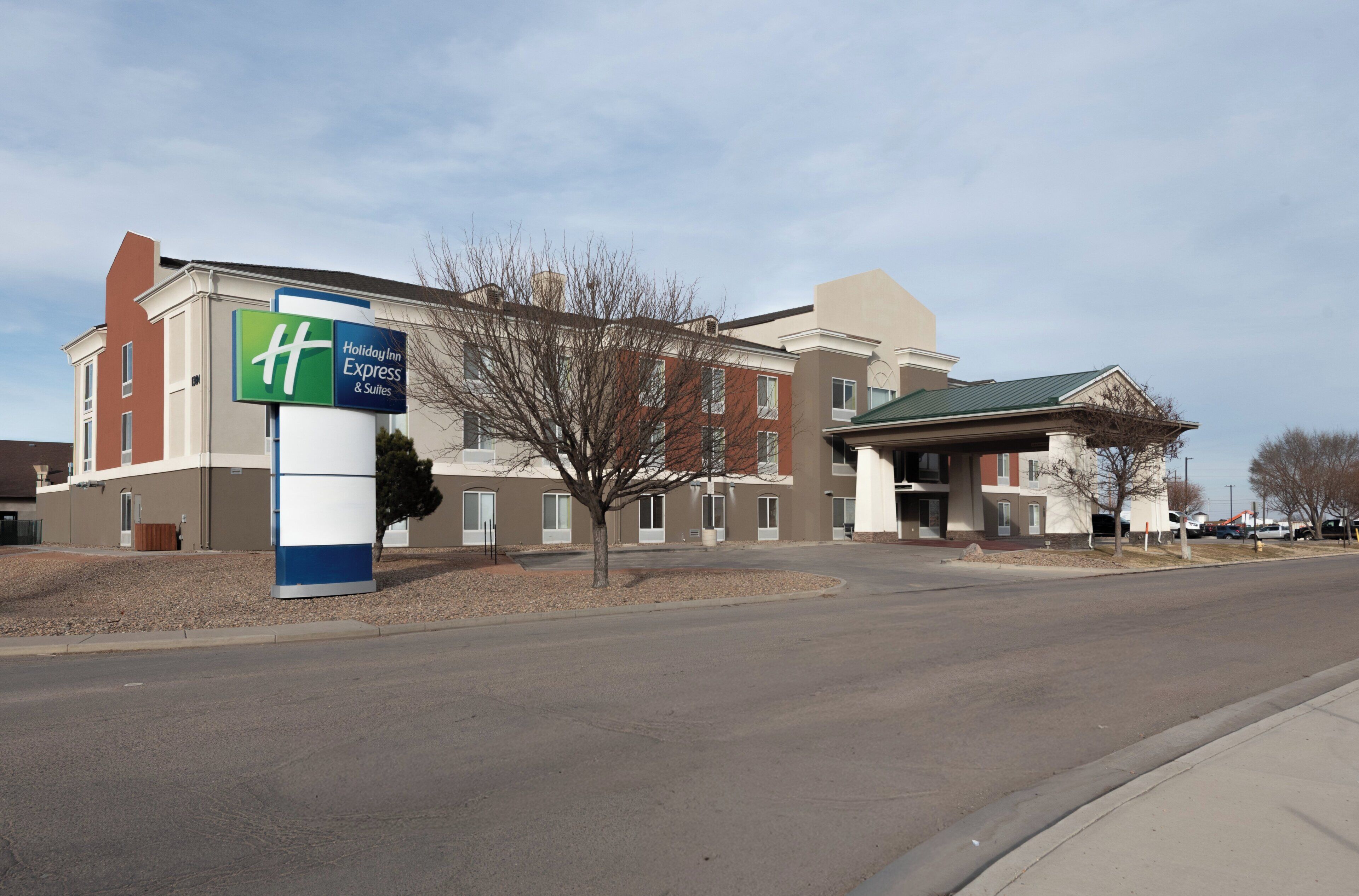 A Holiday Inn Express & Suites hotel with a clear sky and a parking lot.