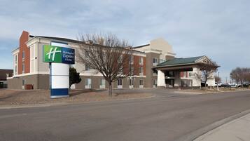 A Holiday Inn Express & Suites hotel with a clear sky and a parking lot.