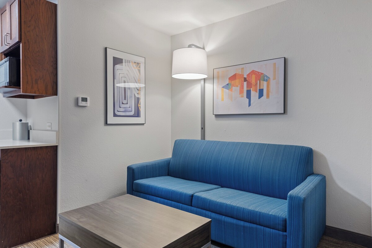 A modern room with a blue sofa, a wooden table, and two framed artworks on the wall.