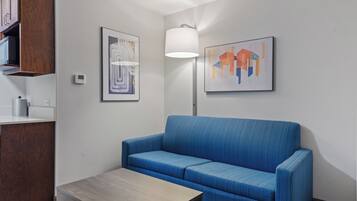 A modern room with a blue sofa, a wooden table, and two framed artworks on the wall.