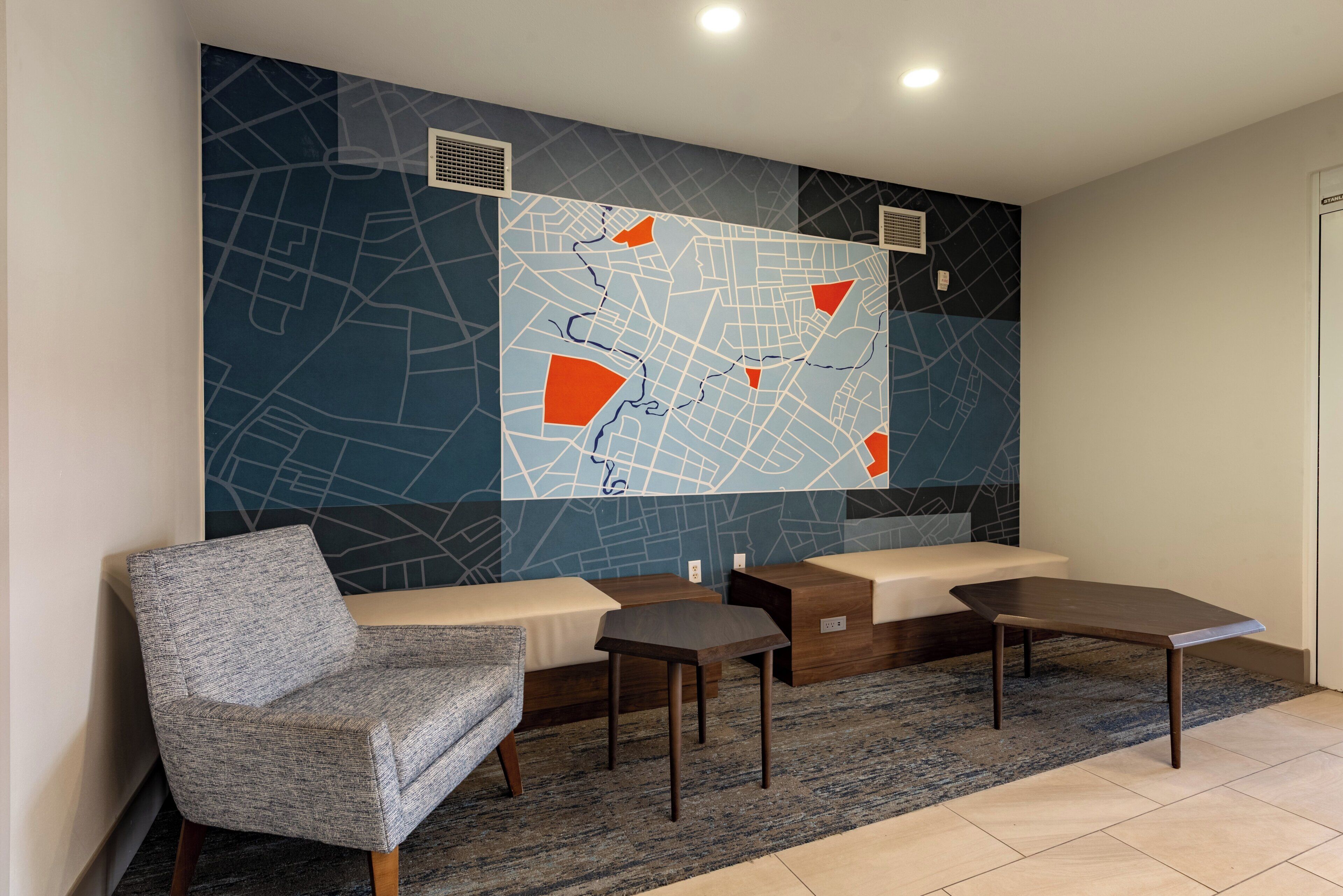 Un espace d’attente moderne doté d’une grande carte murale, de sièges et d’une petite table.