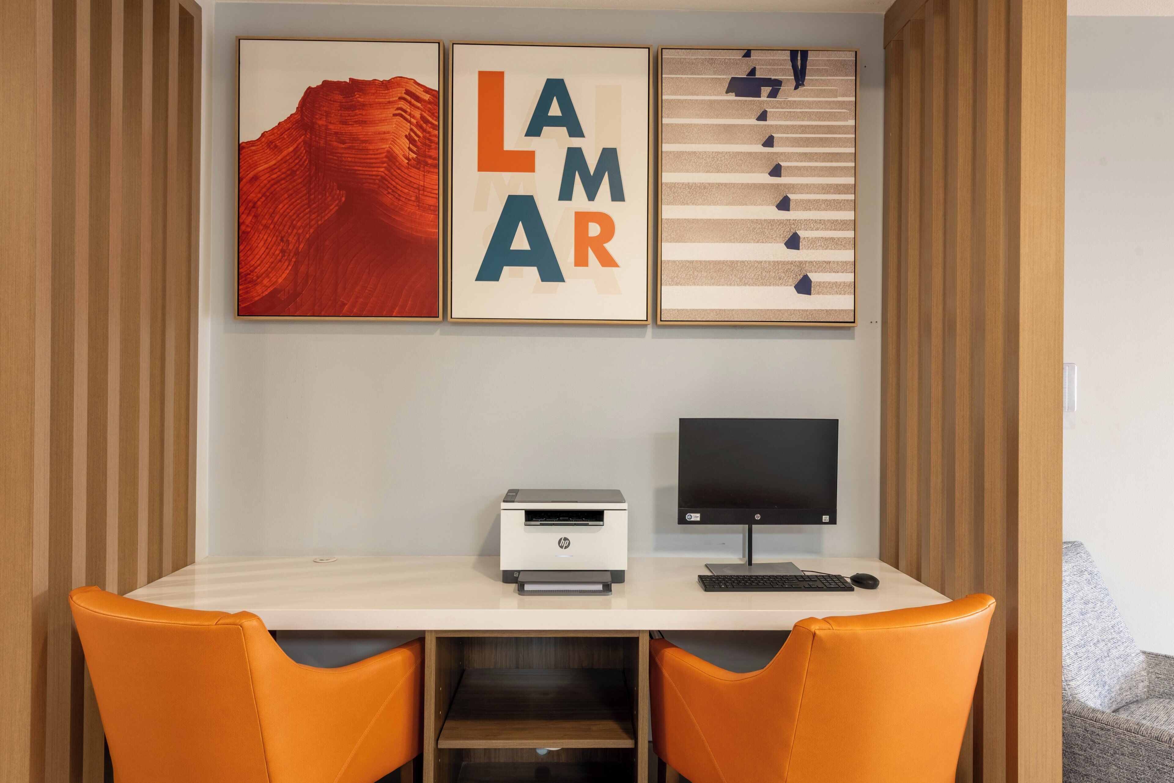 Un espacio de trabajo con un escritorio, dos sillas, una impresora y un monitor.