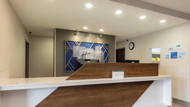 A reception desk with a modern design, a clock on the wall, and a sign indicating a general manager's office.