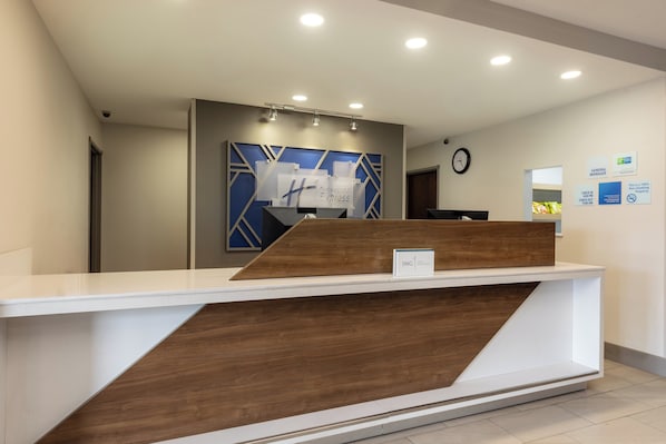 Un comptoir d’accueil au design moderne, une horloge au mur et un panneau indiquant le bureau du directeur général.