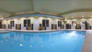Ein Hallenbad mit gefliesten Wänden und Fenstern, mit einigen Stühlen.