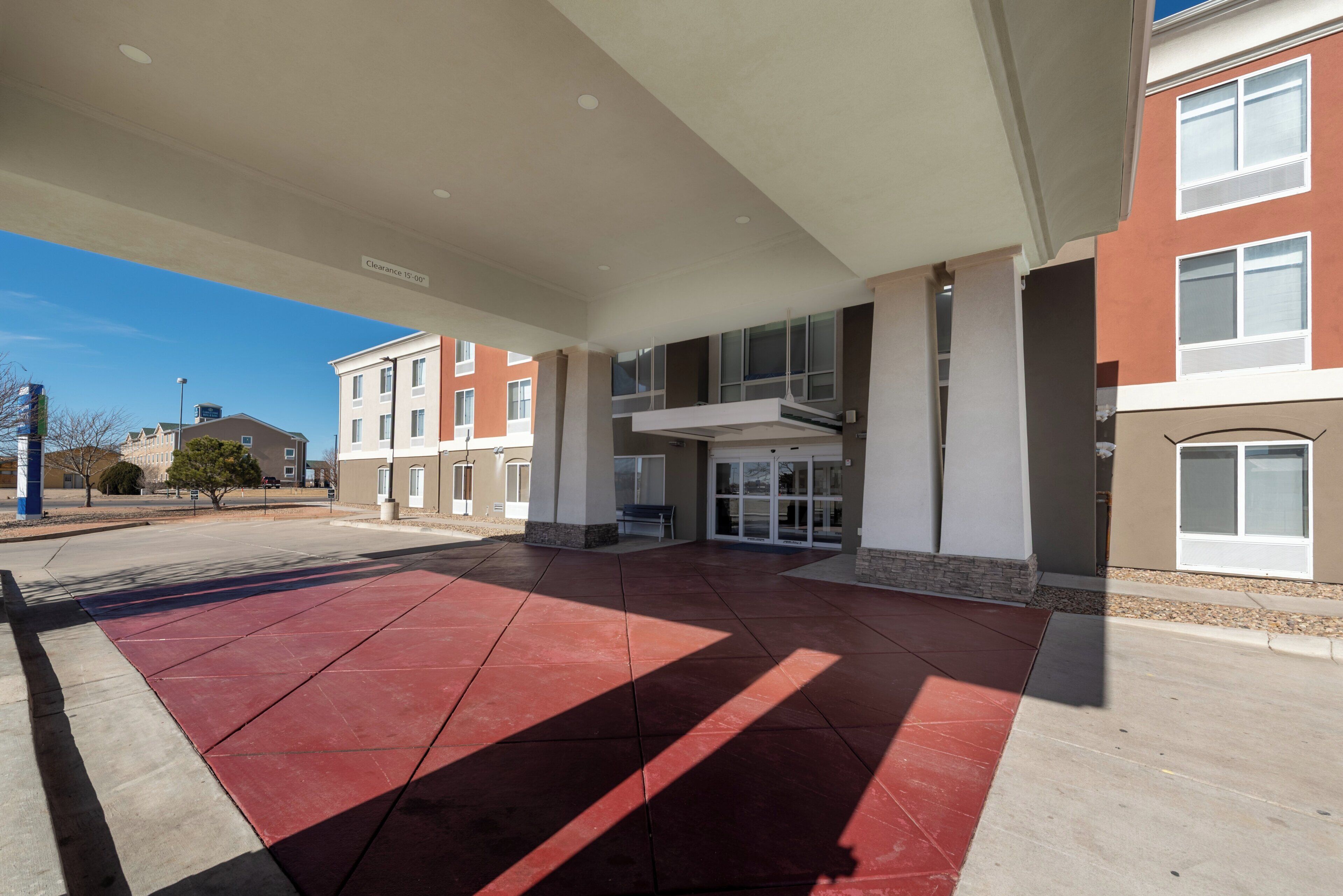A building with a covered entrance, a clear sky, and a parking lot.