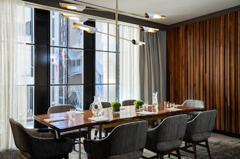 A hotel room with a bed, a sofa, a desk with a lamp, a window with curtains, and a view of buildings. at Kimpton Hotel Palomar Philadelphia by IHG