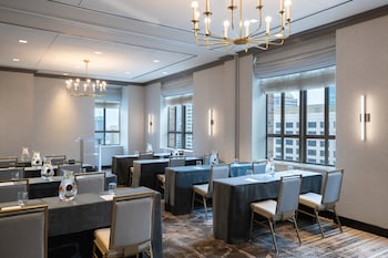A city skyline with modern high-rise buildings, a river reflecting the structures, and a bridge crossing the river. at Kimpton Hotel Palomar Philadelphia by IHG