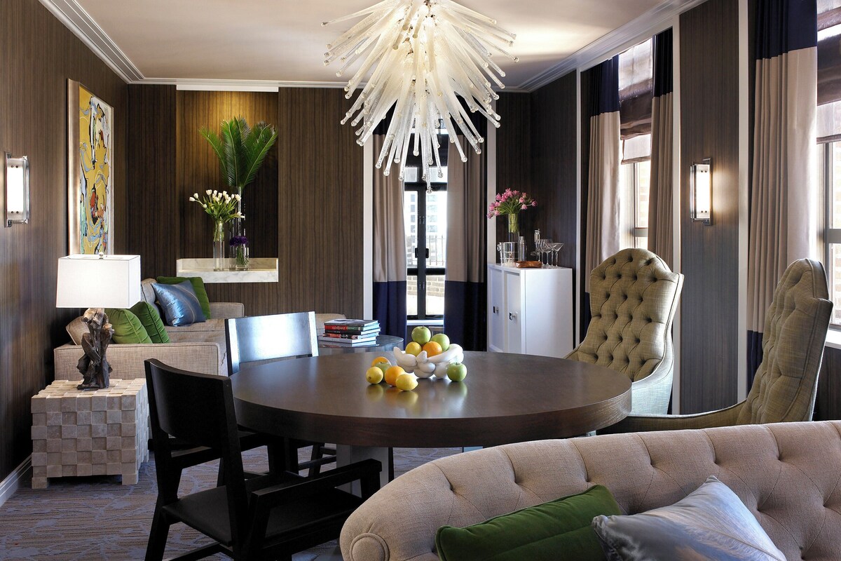 A dining area with a round table, chairs, and a chandelier.