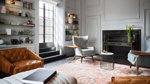 A modern living room with a fireplace, leather armchairs, a bookshelf, and a patterned rug. - Kimpton Hotel Palomar Philadelphia by IHG (Philadelphia)