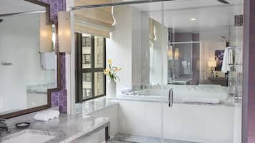 A modern bathroom with a glass-enclosed shower, a large mirror, and a marble countertop.