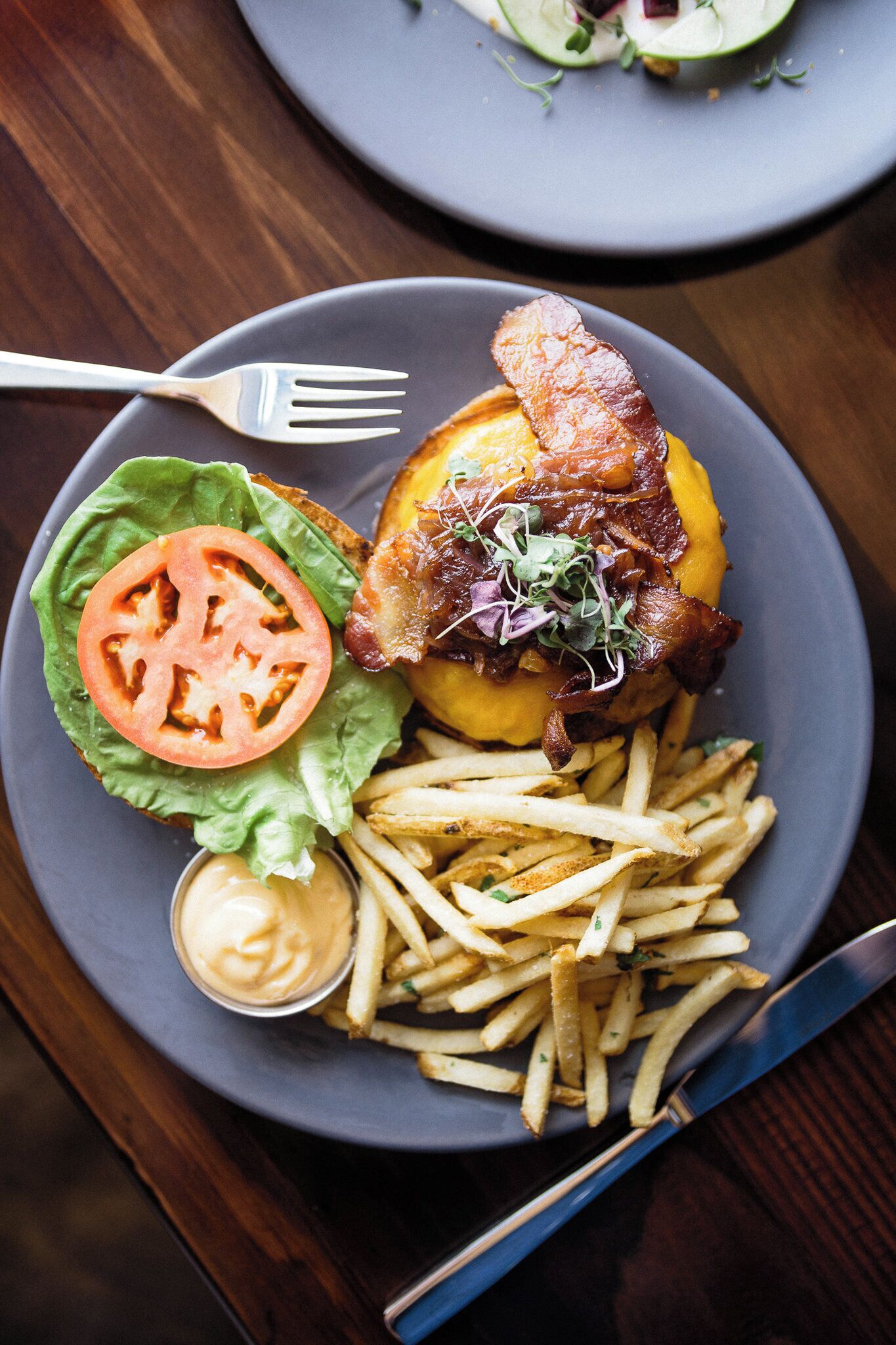 A plate with a burger, fries, and a side of sauce.