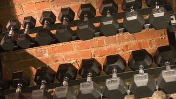 A rack of hexagonal dumbbells with weights ranging from 10 to 45 lbs, arranged against a brick wall.