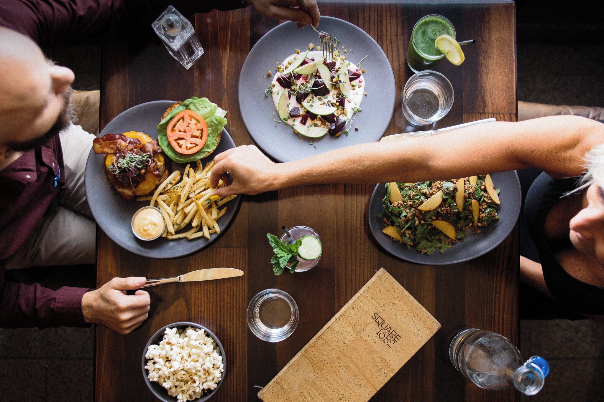 A dining table with plates of food, a bowl of popcorn, and a menu.