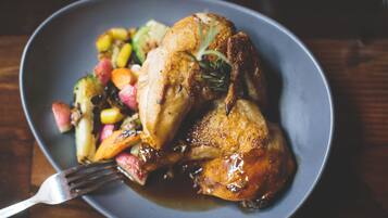 A plate with roasted chicken, vegetables, and gravy.