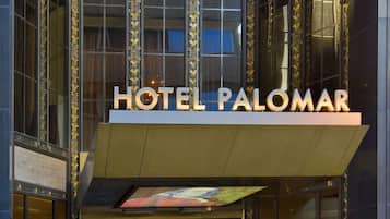 The entrance of Hotel Palomar with a modern facade, large glass windows, and a prominent sign above the entrance.