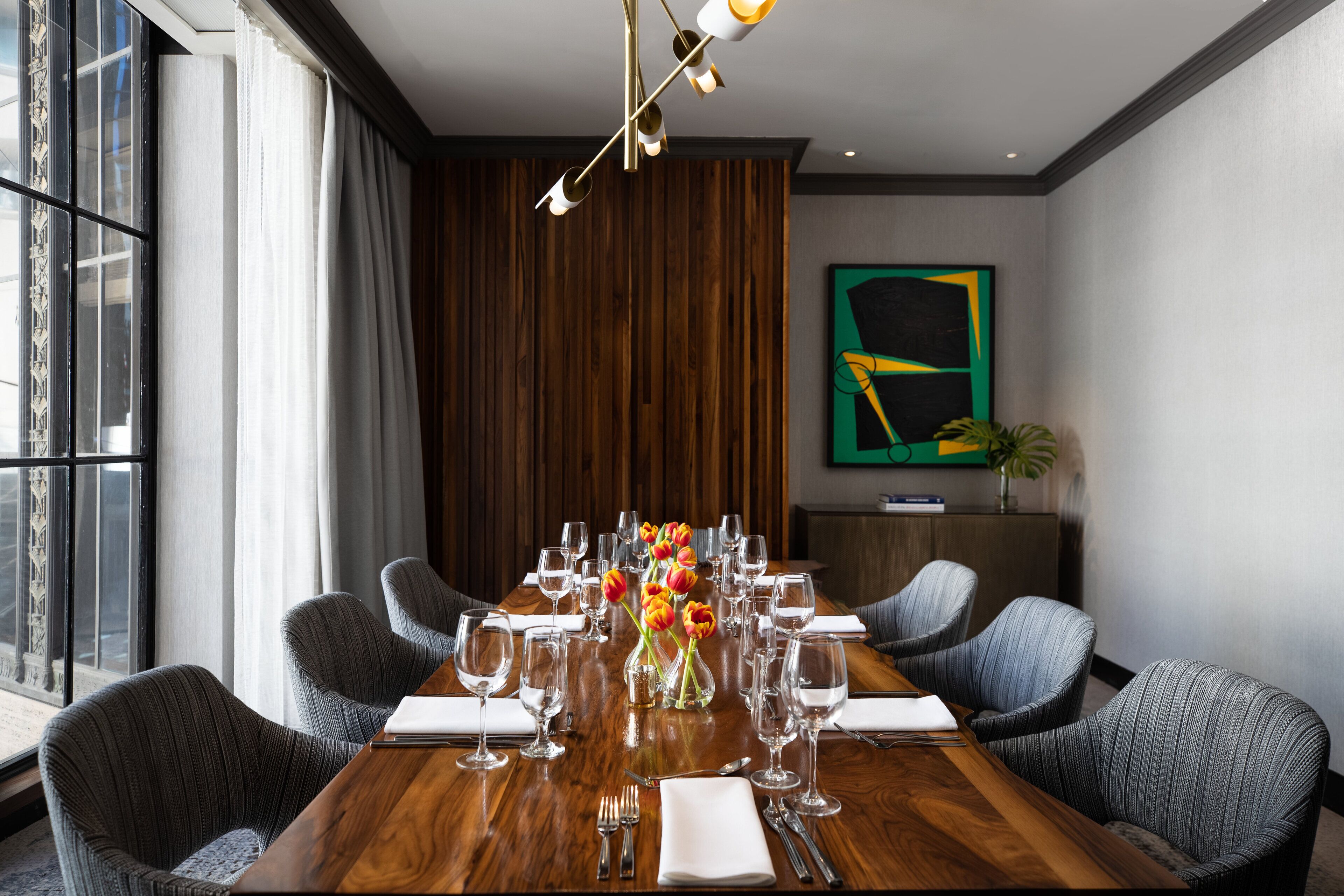 A conference room with a wooden table set for a meeting, surrounded by upholstered chairs.