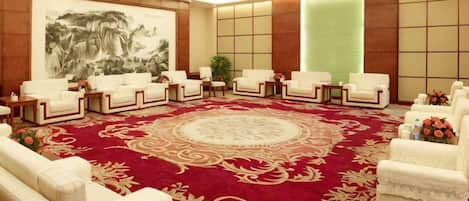 A conference room with a large red carpet, white chairs, and a large painting on the wall.