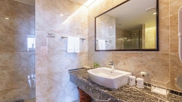 Un baño moderno con lavamanos de mármol, un espejo grande y un perchero para toallas.