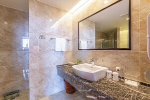 Un baño moderno con lavamanos de mármol, un espejo grande y un perchero para toallas.