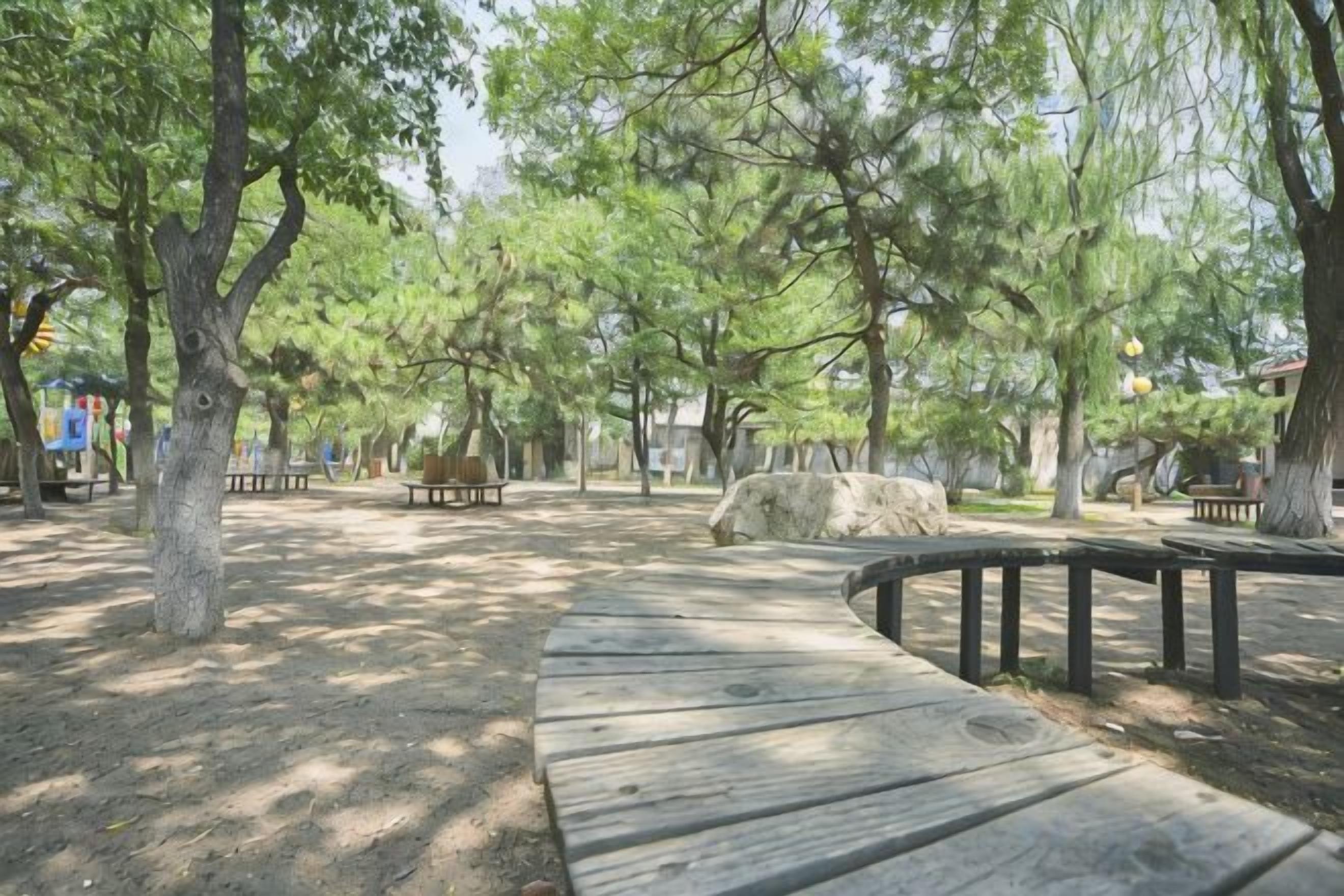 Un parc avec des bancs en bois, un chemin pavé et des arbres.