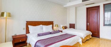 Una habitación de hotel con dos camas, un escritorio, una silla, una lámpara y una puerta.
