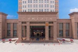 A hotel entrance with a large sign, a staircase leading up to the entrance, and a tiled pavement in front. - Petroleum Hotel (Jinzhou)