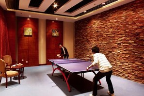 A room with a ping pong table, a red curtain, and a brick wall. - Petroleum Hotel (Jinzhou)