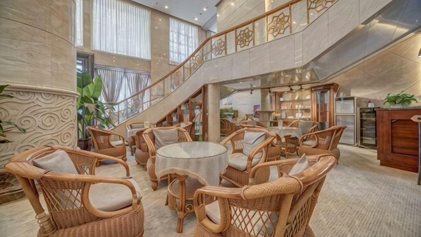 Een ruime lobby met rieten meubels, een trap en uitzicht op het interieur.