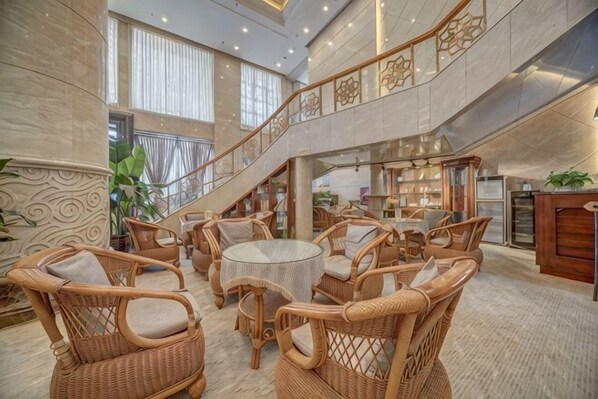 A spacious lobby with wicker furniture, a staircase, and a view of the interior.