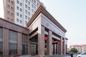 Un hotel de estilo arquitectónico tradicional, con una entrada destacada que incluye columnas grandes y un letrero sobre las puertas.