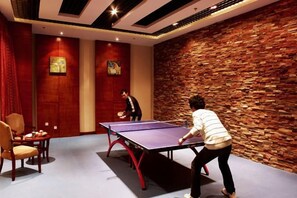 A ping pong table in a room with a stone wall and two paintings on the wall. - Petroleum Hotel (Jinzhou)