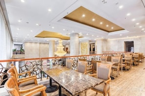 A spacious dining area with a long table and multiple chairs, a decorative light fixture, and a wooden floor. - Petroleum Hotel (Jinzhou)