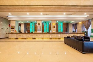 Zona de recepción de un hotel con mostrador de mármol, premios enmarcados y un sofá de cuero.