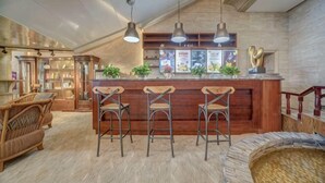 Een bar met houten krukken, een toonbank en hanglampen.