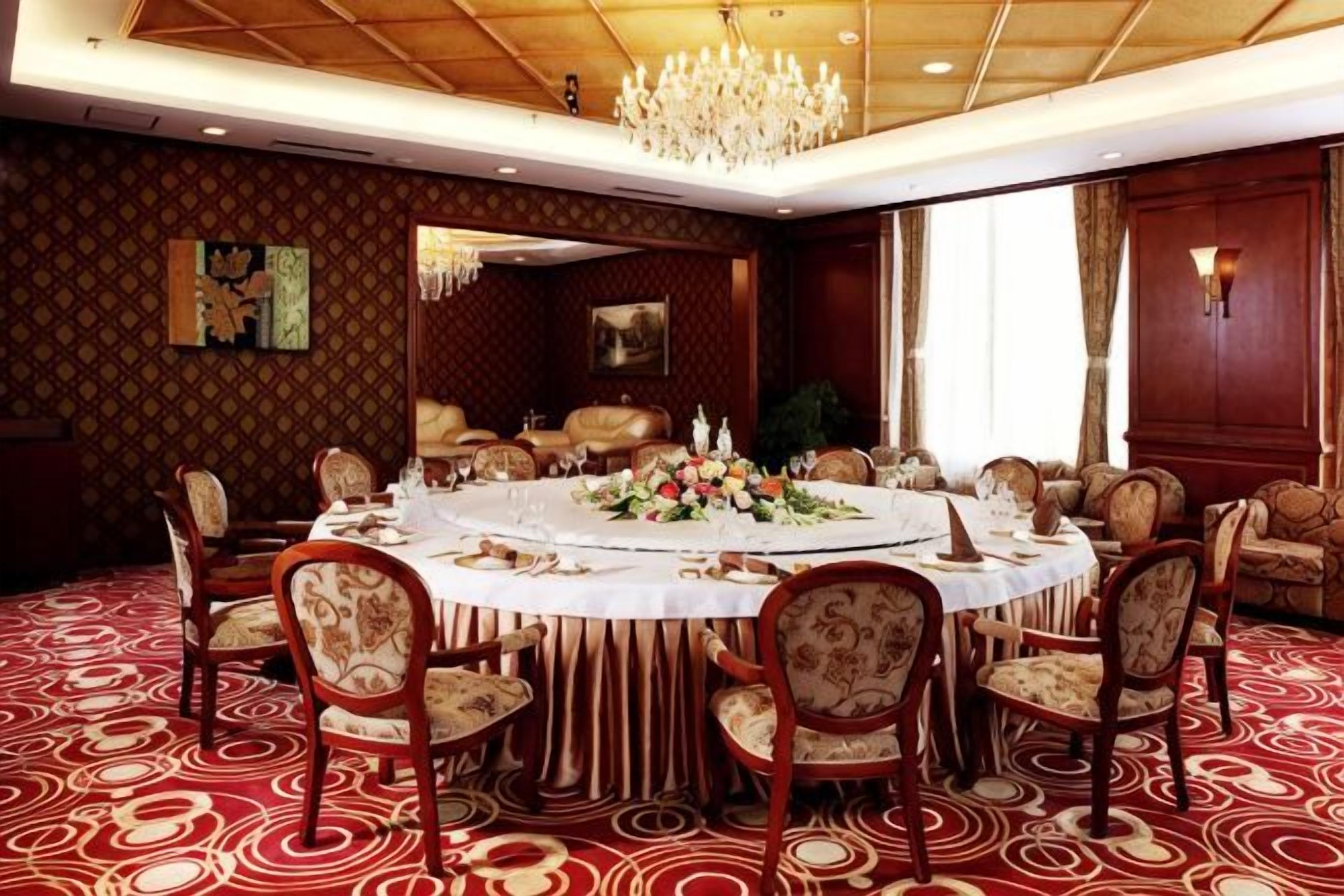 Un comedor formal con una mesa redonda, sillas y una araña.