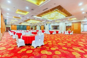 A banquet hall with round tables and white chairs, a red carpet, and a high ceiling with recessed lighting. - Petroleum Hotel (Jinzhou)