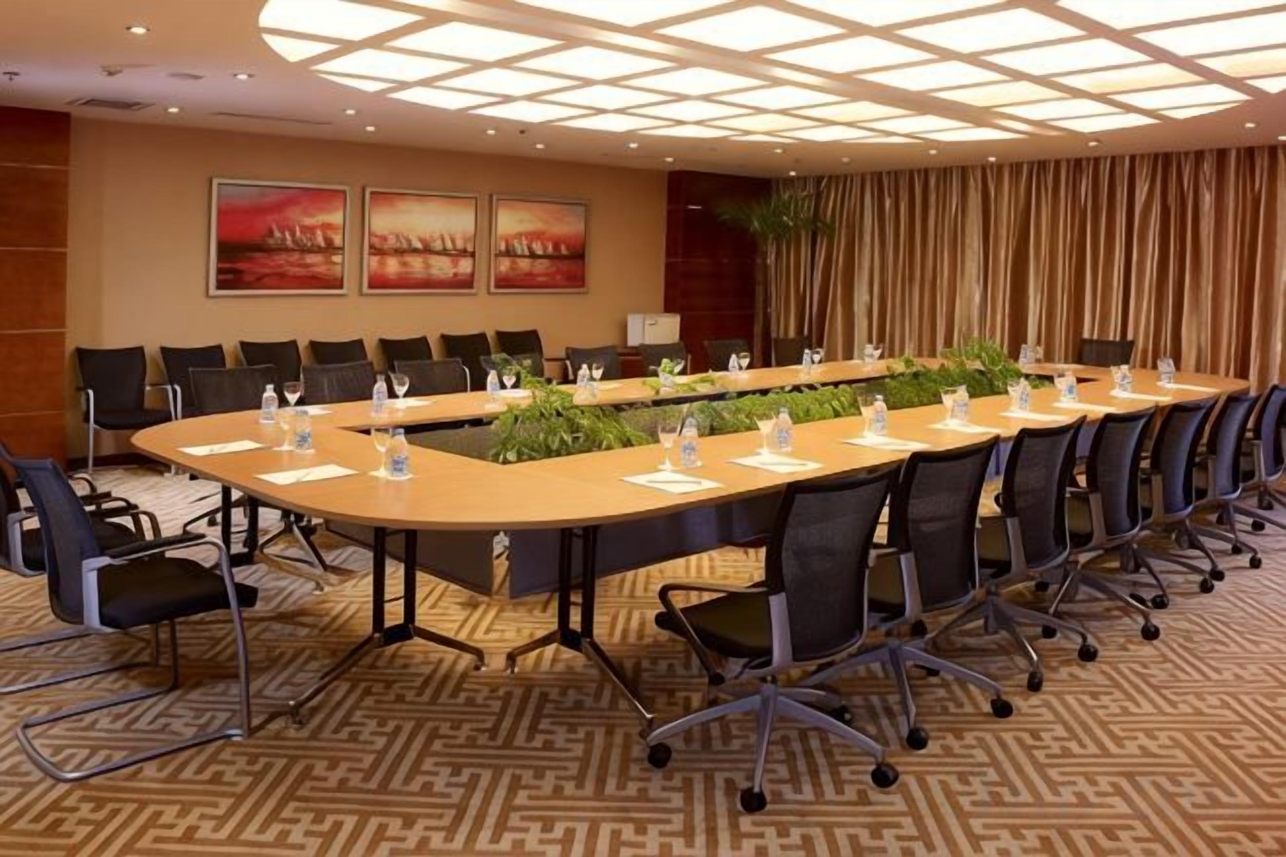 A conference room with a long table, chairs, and a patterned carpet.